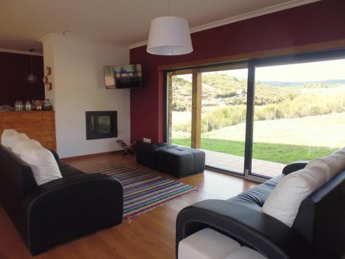 a living room with couches and a large sliding glass door at Quinta do Favacal - Agroturismo - Serra da Estrela in Casegas