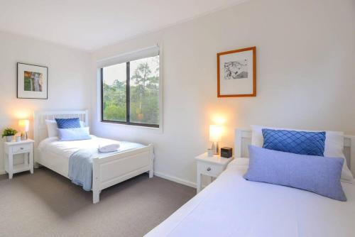 a white bedroom with two beds and a window at Nature Lovers Dream - Hikes & Fireplace in Wentworth Falls