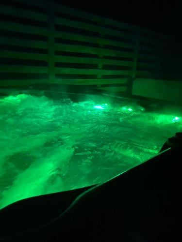 uma piscina de água à noite com luzes verdes em Apartament Masuria SPA Renata Rosłoń em Świętajno