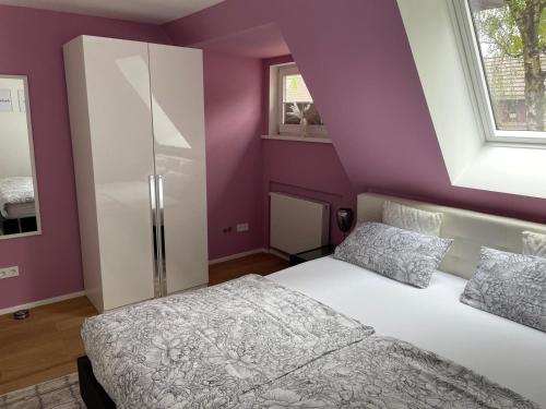 a bedroom with purple walls and a white bed and window at City Wohnung mit Gartenblick und Dachterrasse in Verden