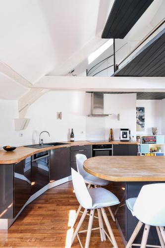 - une cuisine avec une table en bois et des chaises blanches dans l'établissement Triplex de Charme : Terrasse/Vue Panoramique, à Beaune