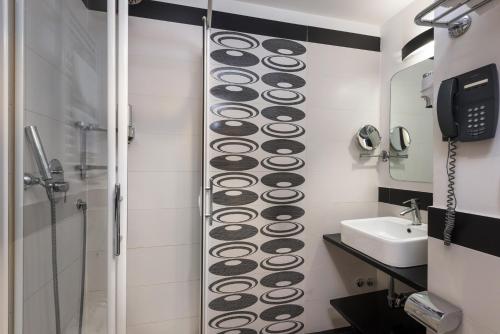 a bathroom with a shower and a sink and a phone at Noba Hotel e Residenze in Rome