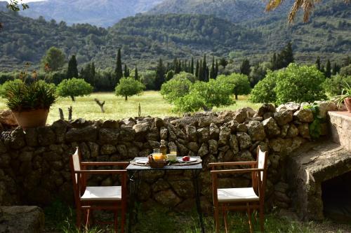a table and chairs with a table and a stone wall at Fangar Agroturismo in Campanet