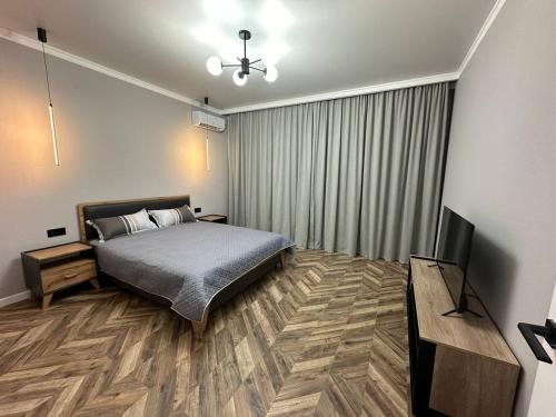 a bedroom with a bed and a flat screen tv at 1-комнатная квартира, 43.7 м², 8/9 этаж посуточно in Zhumysker