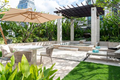 a patio with a table and chairs and an umbrella at Siam Kempinski Hotel Bangkok in Bangkok