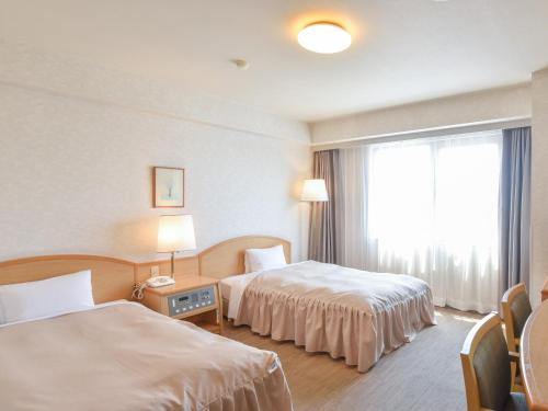 a hotel room with two beds and a window at Yokkaichi City Hotel Annex in Yokkaichi