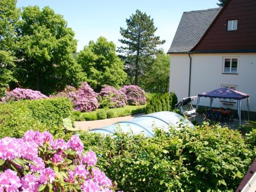 een tuin met roze bloemen en een huis bij Holiday homes for two people with a swimming pool in the Ore Mountains in Pockau