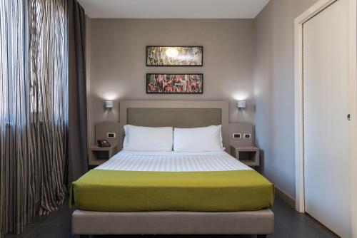 um quarto com uma cama com um cobertor verde e branco em Noba Hotel e Residenze em Roma