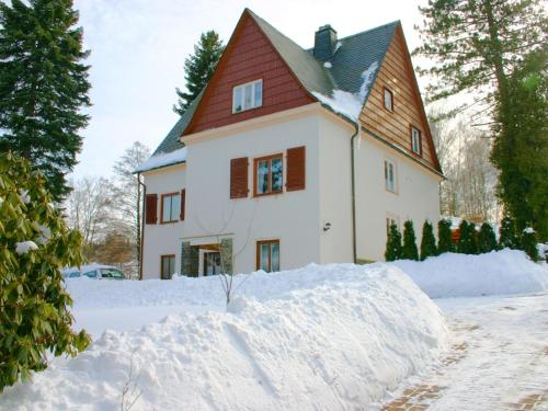 a house with a pile of snow in front of it at Holiday homes for two people with a swimming pool in the Ore Mountains in Pockau
