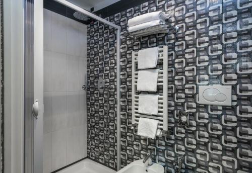 a bathroom with a shower and a toilet and towels at Noba Hotel e Residenze in Rome