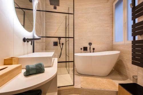 a bathroom with a white tub and a glass shower at Luxueux Logement Grand Place et Opéra clim by Lity in Lille