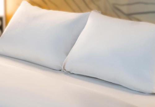 - une paire d'oreillers blancs sur un lit dans l'établissement B&B HOTEL Saint-Witz Roissy, à Saint-Witz