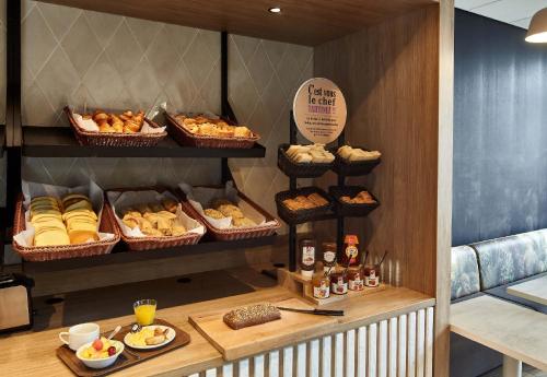 - une boulangerie avec différentes pâtisseries et pains en paniers dans l'établissement B&B HOTEL Saint-Witz Roissy, à Saint-Witz