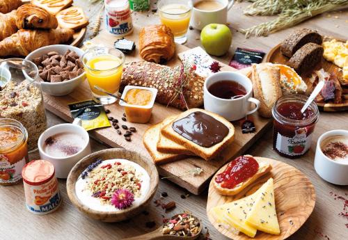 una mesa cubierta con muchos tipos diferentes de alimentos para el desayuno en B&B HOTEL Saint-Witz Roissy en Saint-Witz