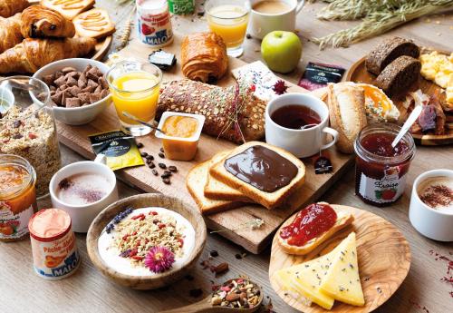 une table avec de nombreux types différents de produits pour le petit-déjeuner dans l'établissement B&B HOTEL Saint-Witz Roissy, à Saint-Witz