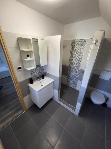 uma casa de banho com um lavatório, um chuveiro e um WC. em WHS Apartments em Monostorapáti