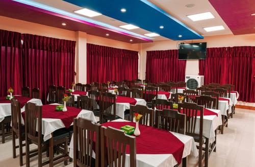 a banquet hall with red curtains and tables and a television at Doleshwor Village Resort & Farm House Pvt. Ltd. in Bhaktapur