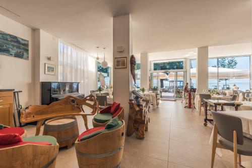 un restaurant avec des chaises, des tables et des fenêtres en bois dans l'établissement Hotel Giardinetto, à Garde