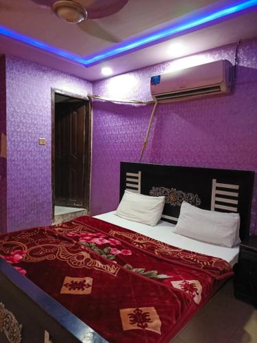 a bedroom with a bed with a purple wall at City Palace Hotel in Lahore