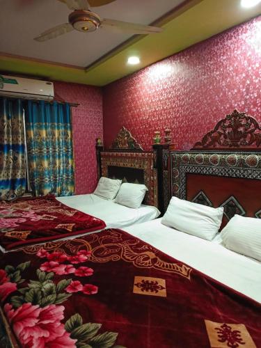 two beds in a bedroom with red wallpaper at City Palace Hotel in Lahore