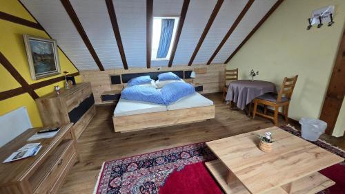 Schlafzimmer mit einem Bett mit blauen Kissen und einem Tisch in der Unterkunft Gasthaus Fuchsacker in Degersheim