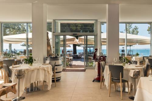 un restaurant avec des tables et des chaises blanches et l'océan dans l'établissement Hotel Giardinetto, à Garde
