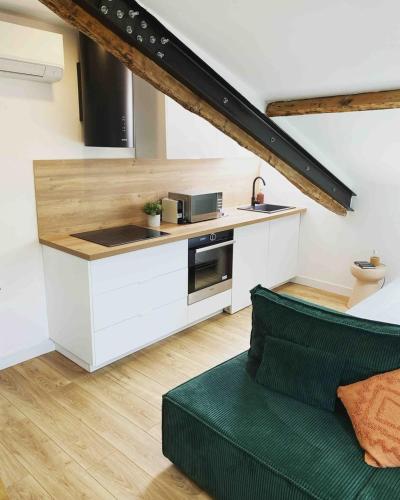 une cuisine avec des placards blancs et un canapé vert dans l'établissement Beautiful refurbished cozy apartment, à Nice