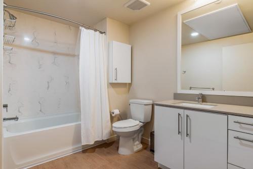 a bathroom with a toilet and a tub and a sink at Blueground Oakland gym wd rooftop nr shops SFO-1683 in Oakland