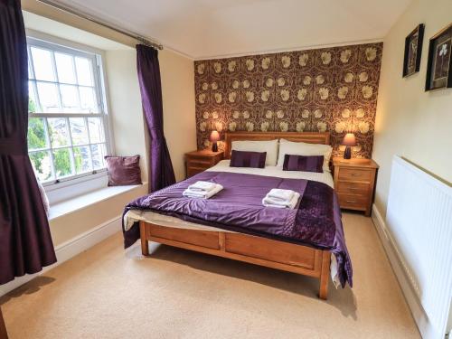 una camera da letto con un letto con lenzuola viola e una finestra di Argyle Cottage ad Ambleside