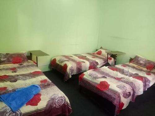カトマンズにあるOm Kedareshwar Boys Hostelの赤いバラが飾られたベッド3台が備わる部屋