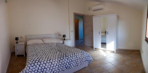 Un dormitorio blanco con una cama y un espejo. en Alba Sarda Residence, en Iglesias
