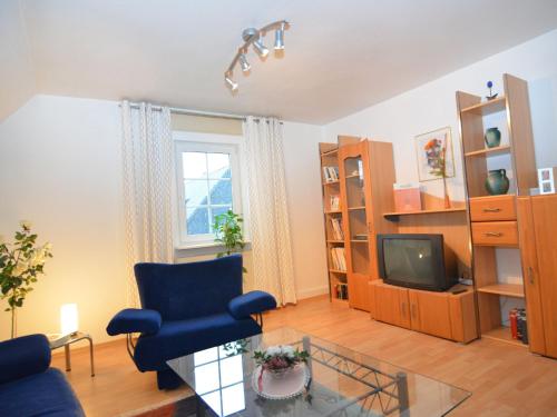 salon z niebieskim krzesłem i telewizorem w obiekcie Apartment near ski area in Wehrstapel in Sauerland w mieście Meschede