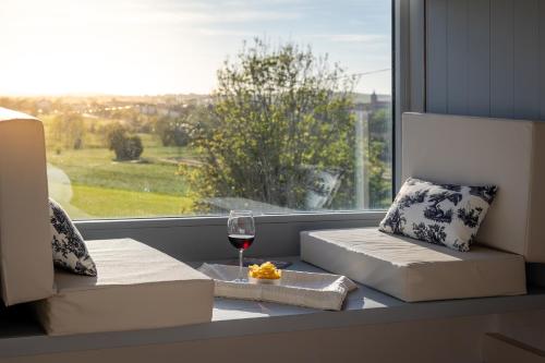 asiento junto a la ventana con una copa de vino y una ventana con vistas en Casona Las Cinco Calderas, en Galizano