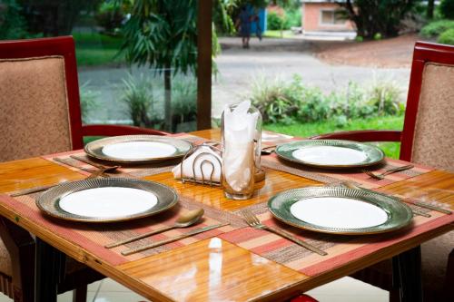 a wooden table with plates and utensils on it at Fatmols City Hotel in Ndola