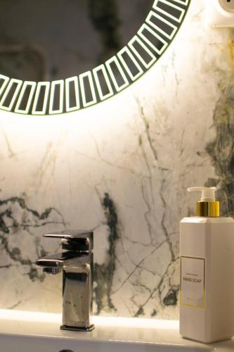 - un lavabo avec une bouteille de savon et un miroir dans l'établissement La Chic Opéra NETFLIX/WIFI, à Marseille