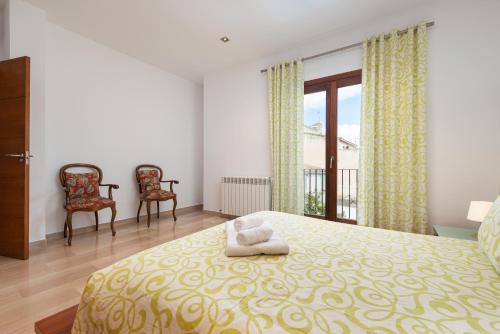 a bedroom with a bed and two chairs and a window at Can Joan -Maria- in Maria de la Salut