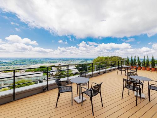 terraza con mesas y sillas en el balcón en Kamenoi Hotel Tsukubasan en Tsukuba