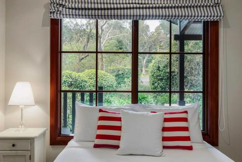 a bed with red and white pillows in front of a window at Mountain Home Leura - Perfect Weekend Escape in Leura