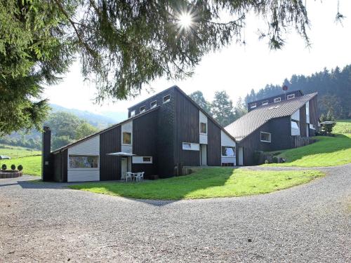 Cosy holiday home in the Hochsauerland with terrace at the edge of the forest في شمالنبرغ: منزل أسود على تلة مع ممر الحصى