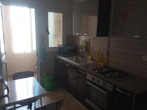 a kitchen with a stove and a sink and a table at Paradise Days in Sfax