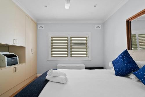 1 dormitorio con 1 cama blanca grande con almohadas azules en Relaxed Clovelly Beach Home - Parking - Cloey6 en Sídney