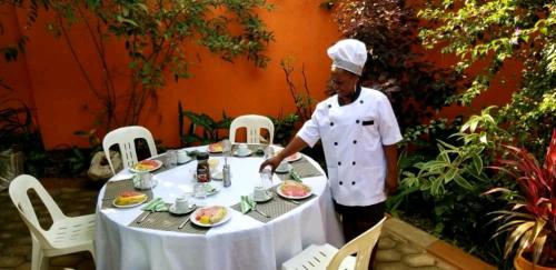 een chef die voor een tafel staat met eten bij Nilenian Holiday Villas in Jinja
