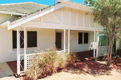 a white house with a porch with a fence at Central to town - Vintage and cosy entire home in Geraldton