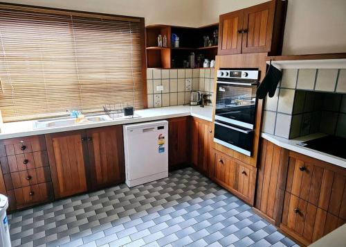 a kitchen with wooden cabinets and a white dishwasher at Central to town - Vintage and cosy entire home in Geraldton