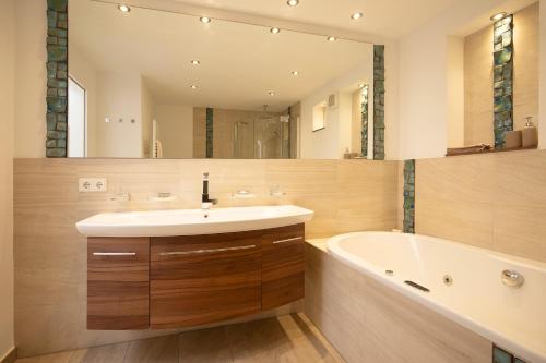 a bathroom with a sink and a tub and a mirror at Biloba Garden in Wengern