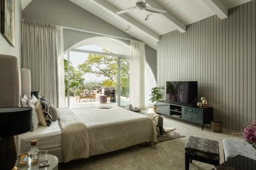 a bedroom with a bed and a large window at Dream By Tellado Villas in Goa