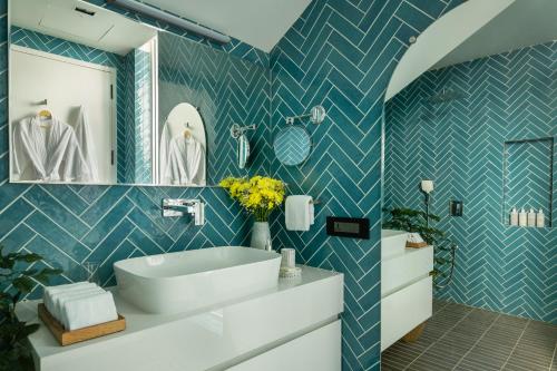 a bathroom with a white sink and blue tiled walls at Dream By Tellado Villas in Goa