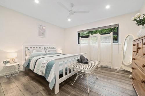 a white bedroom with a white bed and a window at Joan's Beach Cottage in Mount Martha