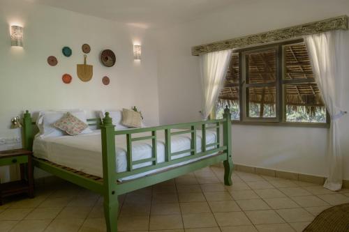 a bedroom with a green bed and a window at Temple Point Resort in Watamu