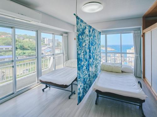 a room with two beds and large windows at Guest Living Mu Nanki Shirahama in Shirahama
